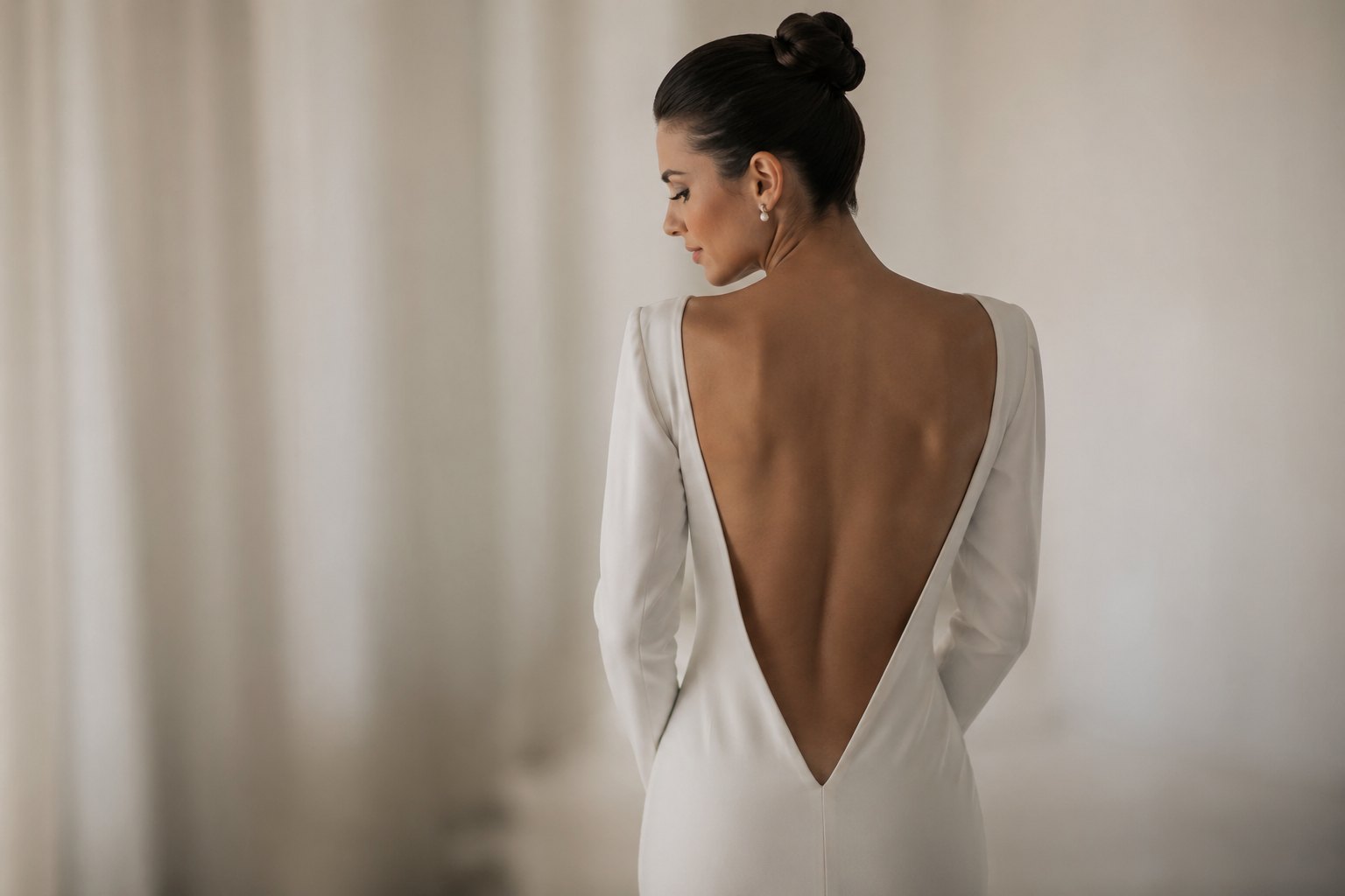 Novia con recogido alto y vestido con escote en V profundo en la espalda, peinado elegante que muestra toda la espalda descubierta